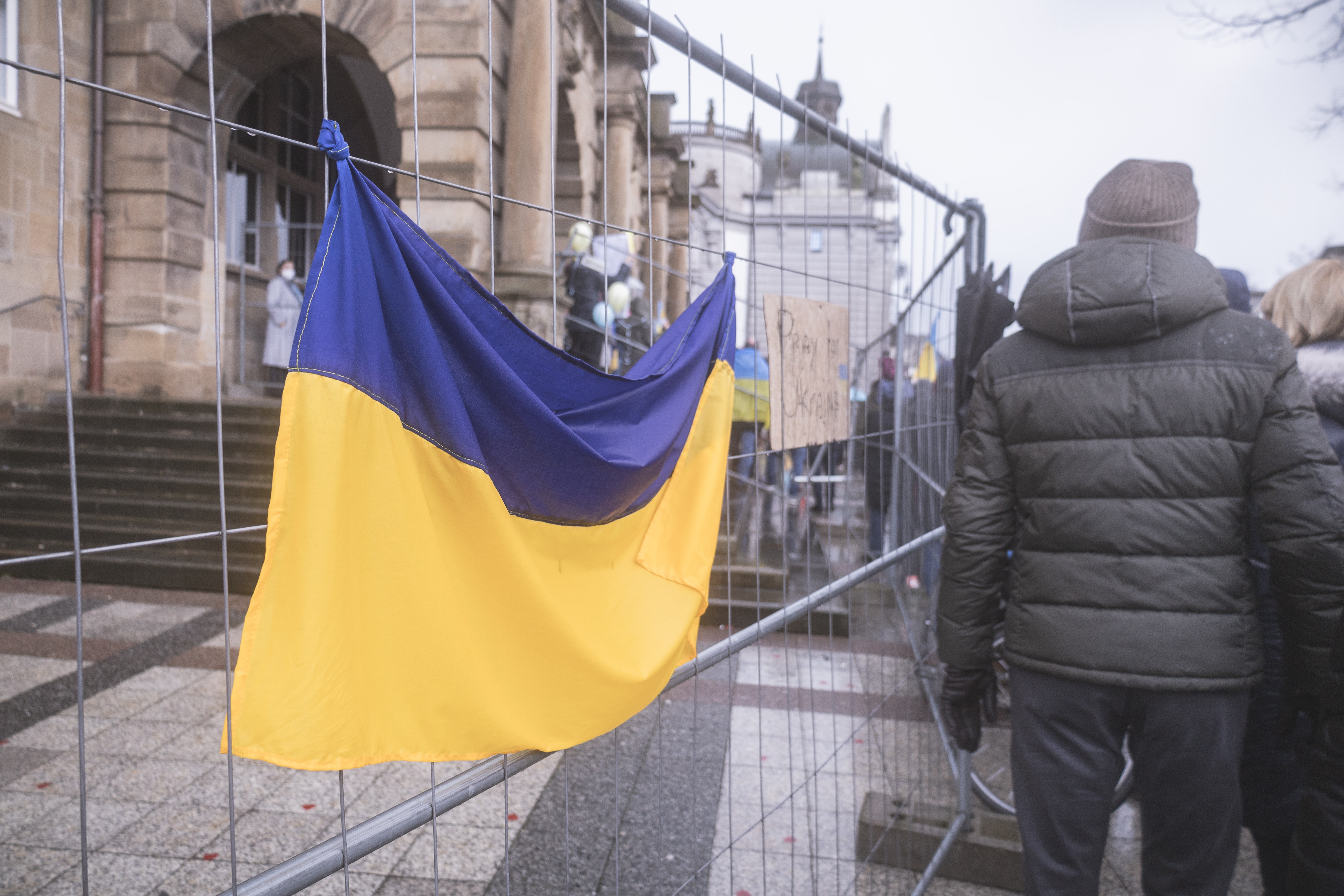 Man's back with Ukraine flag hanging on fence